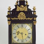 A large bracket clock in solid oak and veneered in ebony decorated with gilt brass mounts